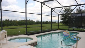 A swimming pool with a hot tub, lounge chairs, and a view of the surrounding landscape.