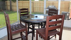 A round glass table with four wooden chairs, a barbecue grill, and a wooden fence in the background. - Stunning 2BR Ranch, perfect for snowbirds or small families (Holiday)