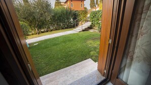 A view from a room with a wooden door leading to a garden with a stone staircase and a building in the background. - Residence Don - pool, garden, 200m to the lake (Bardolino)