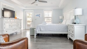 Une chambre à coucher comprenant un lit, une commode, un téléviseur et un ventilateur de plafond.