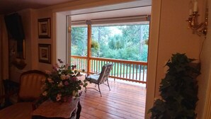 Une terrasse en bois avec une chaise et une table agrémentée d’un arrangement floral.