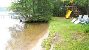 A lakeside scene with a playground, including a slide and swings, and a row of chairs facing the water. - Beautiful Cabin on the Inland Chain of 28 beautiful Lakes .
(Eagle River)