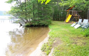 A lakeside scene with a playground, including a slide and swings, and a row of chairs facing the water. - Beautiful Cabin on the Inland Chain of 28 beautiful Lakes .
(Eagle River)