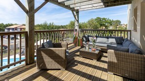 A wooden deck with wicker furniture, a pool, and a view of a residential area. - 4* Gallery Villa in Moliets, 15 p, heated pool, ensuite rooms/ close 2 beach (Moliets-Et-Maa)