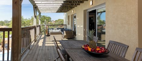 Una terraza de madera con una mesa y sillas, un cuenco de fruta y vistas del paisaje circundante.