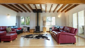 A spacious living room with wooden beams, leather sofas, a cowhide rug, and a wood-burning stove. - 4* Gallery Villa in Moliets, 15 p, heated pool, ensuite rooms/ close 2 beach (Moliets-Et-Maa)