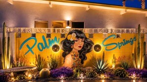 Une façade d’immeuble avec l’inscription « Palm Springs » et une fresque représentant une femme.