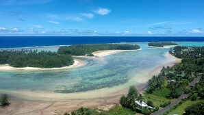 Paisagem costeira com águas azul-claras, praias arenosas e vegetação densa.