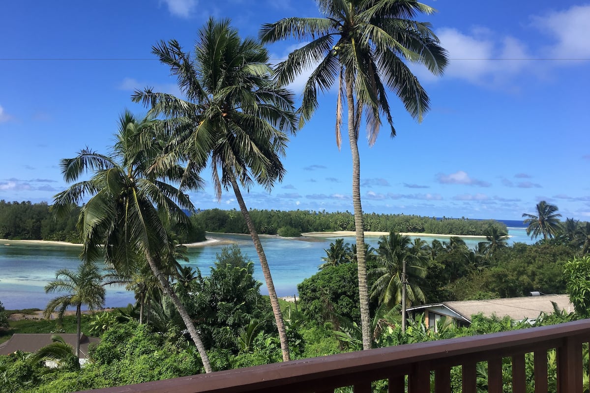 A tropical beach view with palm trees and a clear sky.