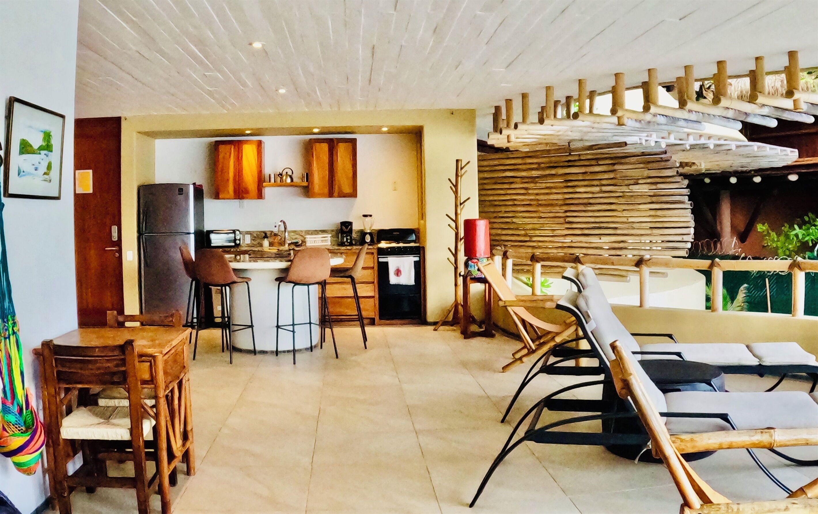 A kitchen with wooden cabinets, a refrigerator, and a dining area with chairs and a table.