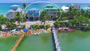 Una propiedad costera con varias edificaciones, un muelle con kayaks y vista al océano.