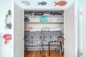 Ein begehbarer Kleiderschrank mit mehreren Regalen für gefaltete Kleidung, ein Bett mit Stauraumschubladen und ein Schuhregal.