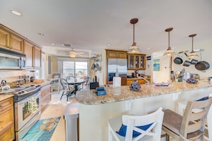 A spacious kitchen with granite countertops, wooden cabinets, and a central island with bar seating.