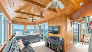 Une pièce spacieuse avec un grand lit, un canapé, une télévision et un ventilateur de plafond.