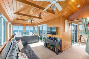 A spacious room with a large bed, a sofa, a TV, and a ceiling fan.