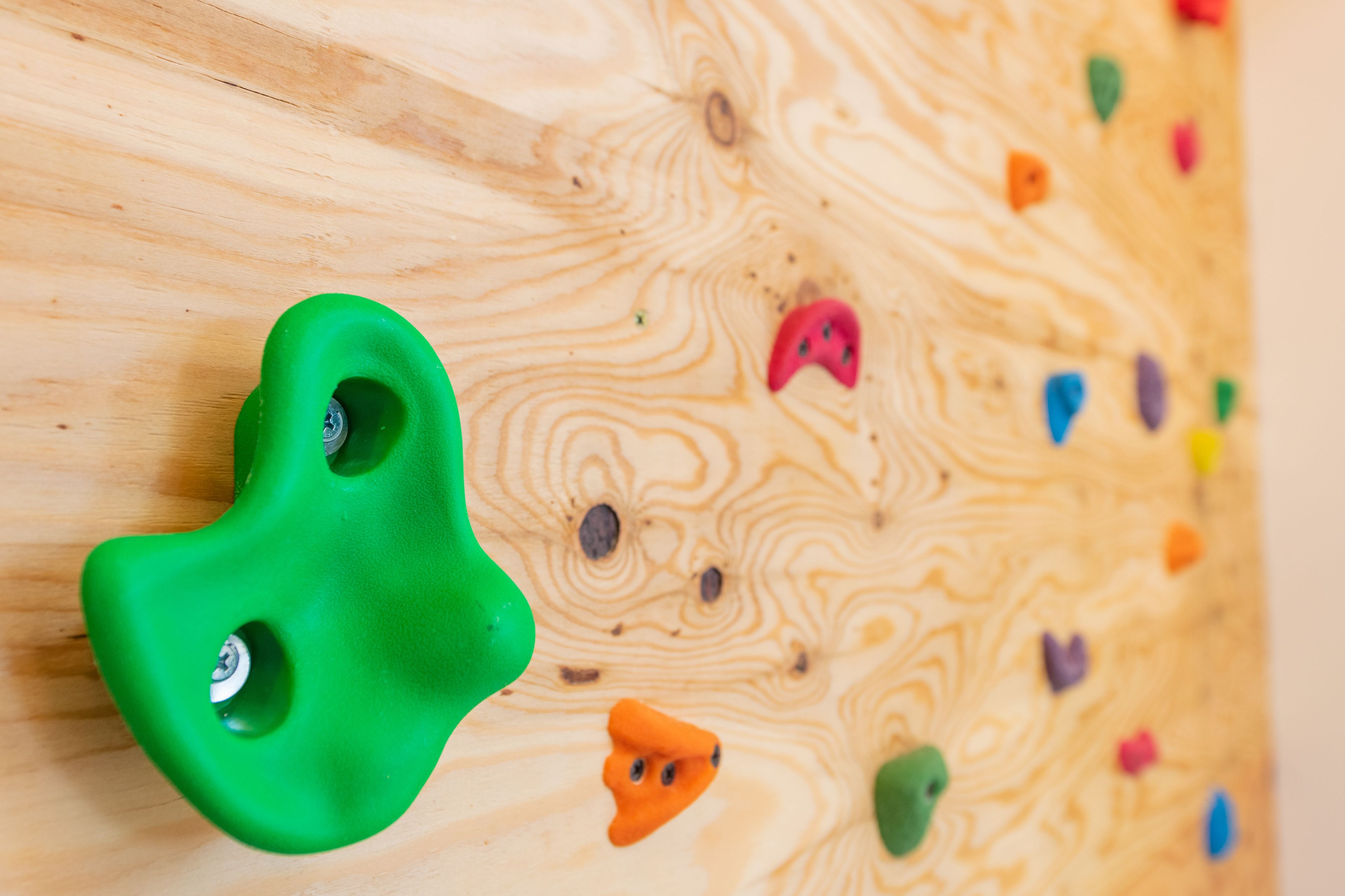 Eine Holzkletterwand mit verschiedenen farbigen Griffen.