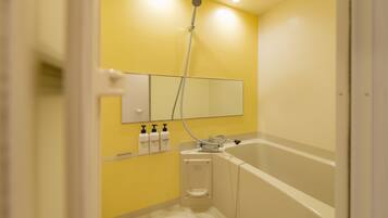 A bathroom with a yellow wall, a white bathtub, and a handheld showerhead.