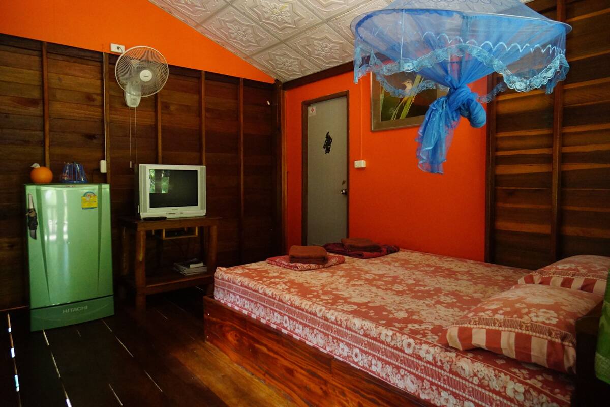 Une chambre équipée d’un lit, d’une télévision, d’un réfrigérateur et d’un ventilateur.