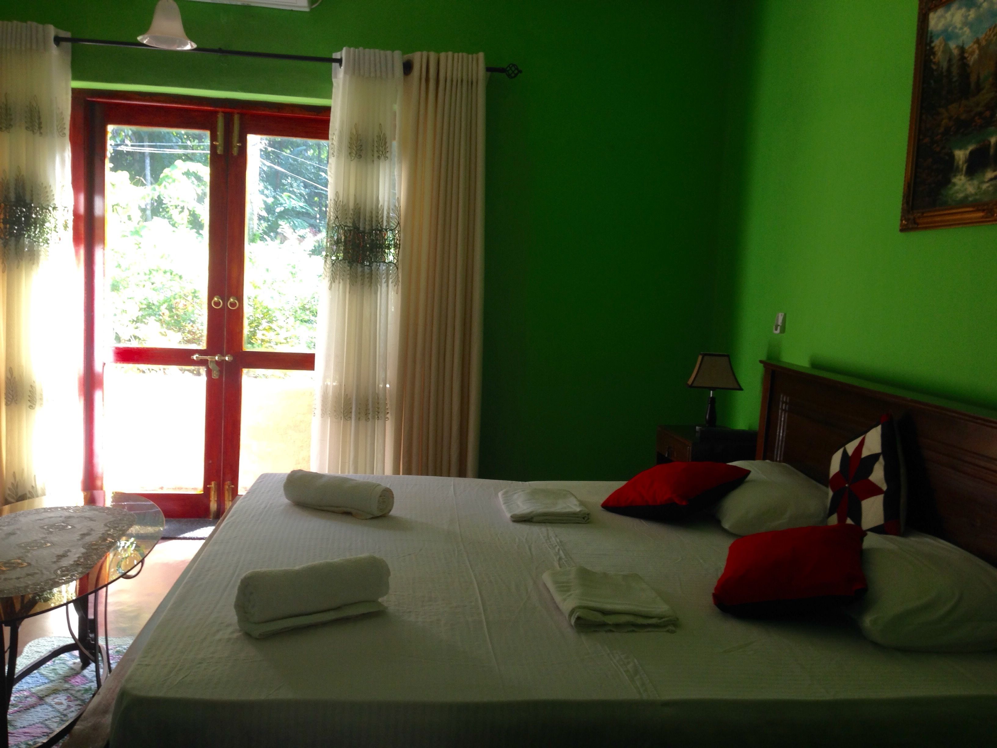 Quarto de hotel com cama, almofadas, mesa de cabeceira, luminária e um quadro na parede.
