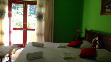 Quarto de hotel com cama, almofadas, mesa de cabeceira, luminária e um quadro na parede.