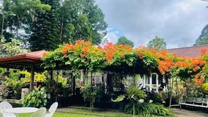 A garden with a gazebo, a white fence, and a bench. - Yalegoda Walauwa Homestay (Udunuwara)