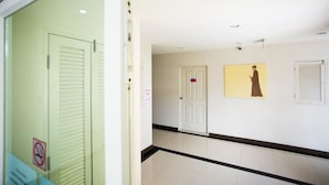 A hallway with a glass door, a white door, and a wall-mounted picture. - Central Residences (Wichit)