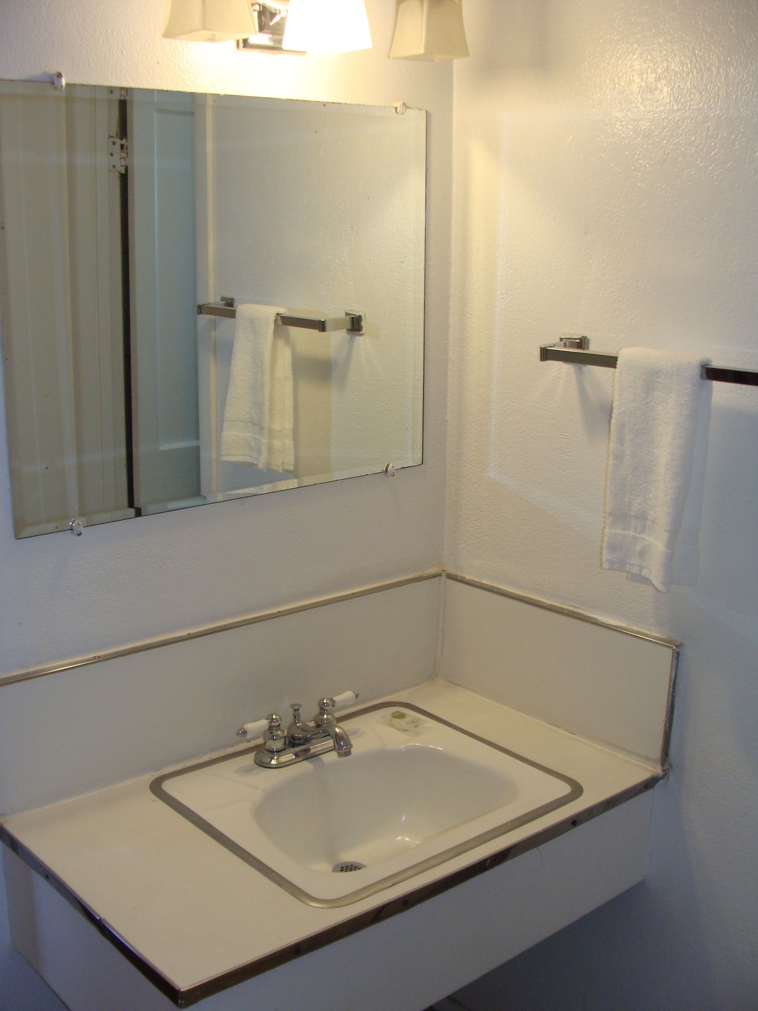A bathroom with a white sink, a mirror, and two towel racks.