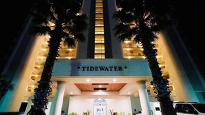A hotel named 'Tidewater' with a central tower, palm trees, and a well-lit entrance. - ROMANTIC MALIBU ELEGANCE - on HGTV & DIRECTLY on the LUMINOUS GULF SAND! (Orange Beach)