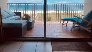 A balcony with a view of the beach, a sofa, a chair, and a small table with a cat. - ROMANTIC MALIBU ELEGANCE - on HGTV & DIRECTLY on the LUMINOUS GULF SAND! (Orange Beach)