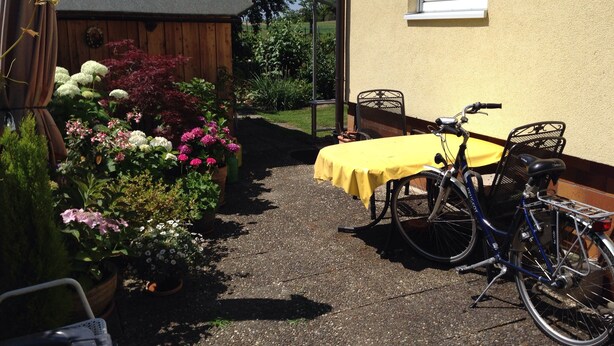 A patio area with a table and chairs, a bicycle, and potted plants. - Between Breisach and Staufen (Bad Krozingen)