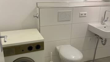 Een bad/douchecombinatie, een haardroger, handdoeken