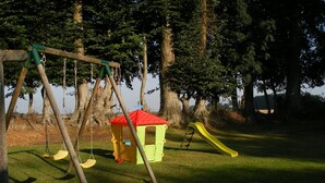 Une aire de jeux avec des balançoires, un toboggan et une petite maison de jeu.