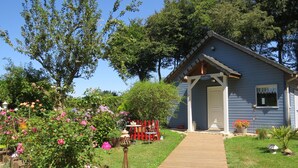 Une maison bleue avec une terrasse en bois donnant sur un porche.