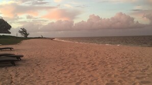 A beach with a clear sky and a few clouds. There are wooden benches along the shore. - 1 br 1ba Ocean Front Condo with amazing Sunrises (Providenciales)