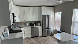 A modern kitchen with white cabinetry, a stainless steel refrigerator, a dishwasher, and a coffee maker. - 1 br 1ba Ocean Front Condo with amazing Sunrises (Providenciales)