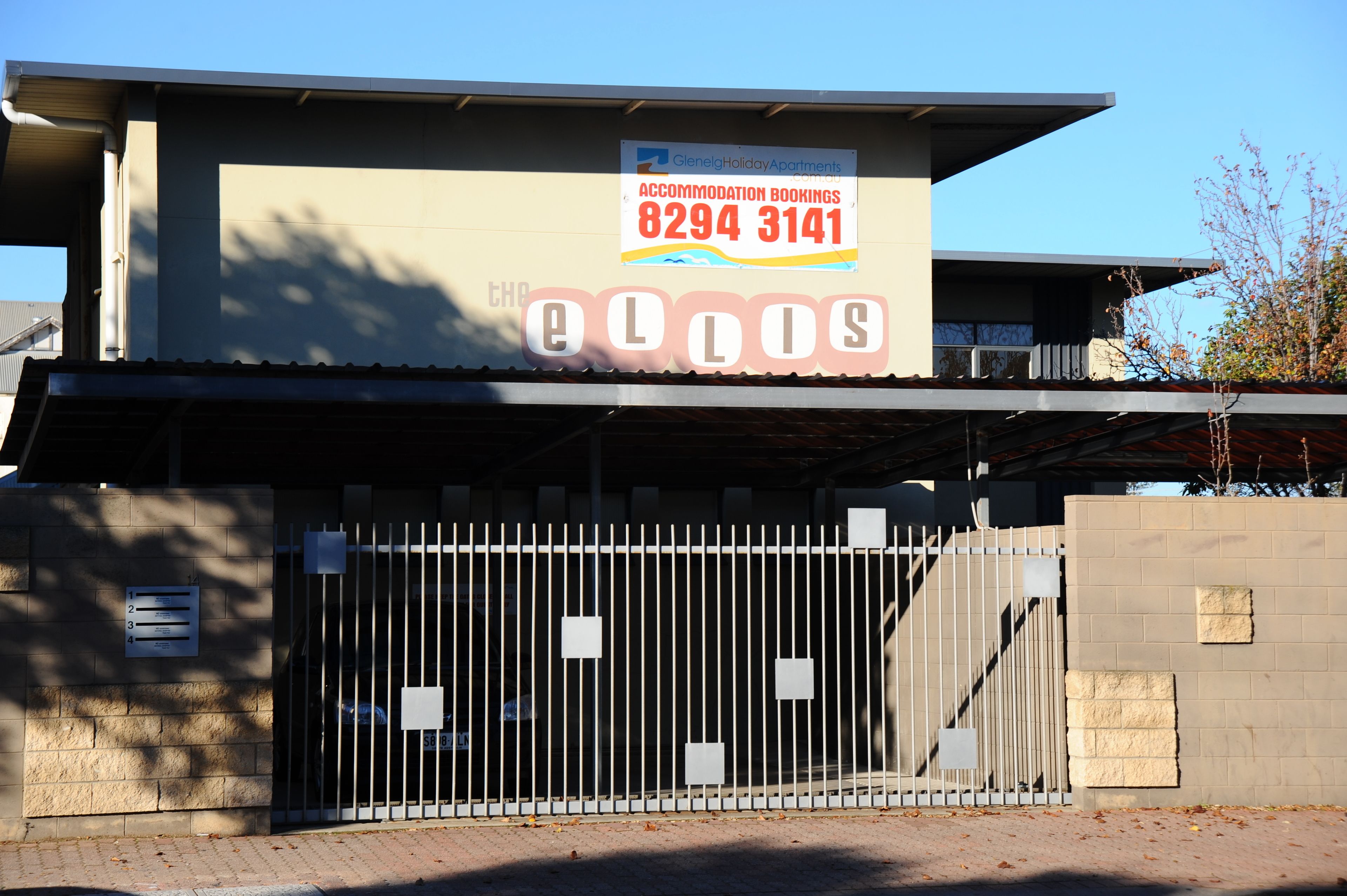 A modern building with a sign for Glenlea Holiday Apartments and a gated entrance.