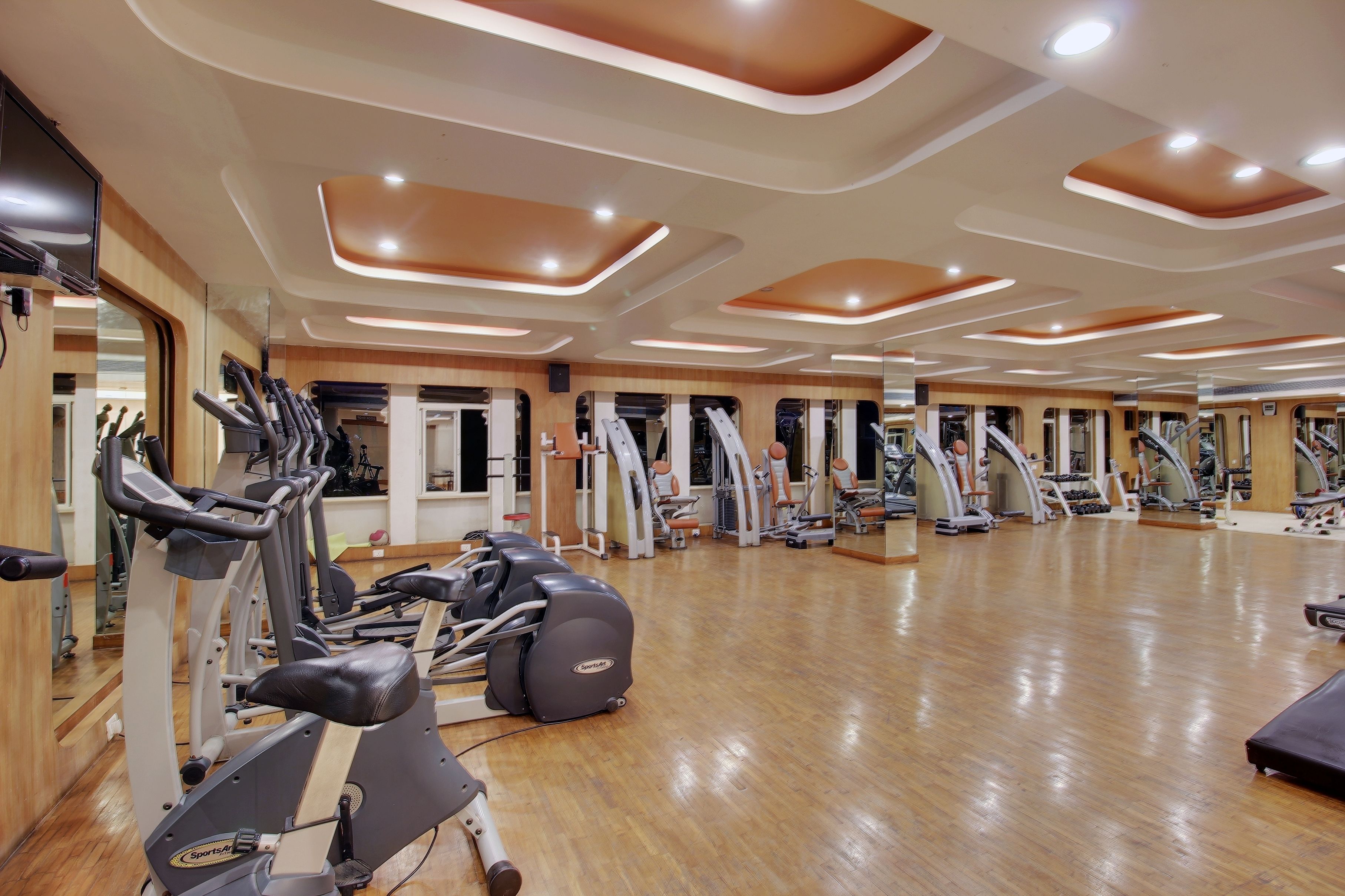 Une salle de sport équipée de plusieurs tapis de course, d’appareils elliptiques et de machines de musculation.