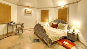 A bedroom with a bed, bedside table, lamp, and a small table with chairs. - Gateway Kandla Gandhidham (Anjar)