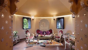 A traditional room with ornate decor, including a sofa set, patterned rugs, and wall-mounted lamps.