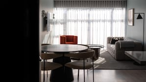 Un salon moderne avec une table de salle à manger ronde, deux fauteuils, un canapé et une table basse.