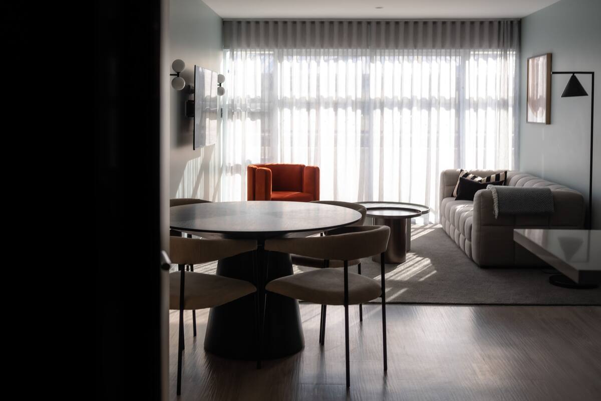 A modern living room with a round dining table, two armchairs, a sofa, and a coffee table.