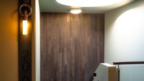Un intérieur moderne avec un mur en bois, un panneau indiquant le numéro « 206 » et un luminaire circulaire.