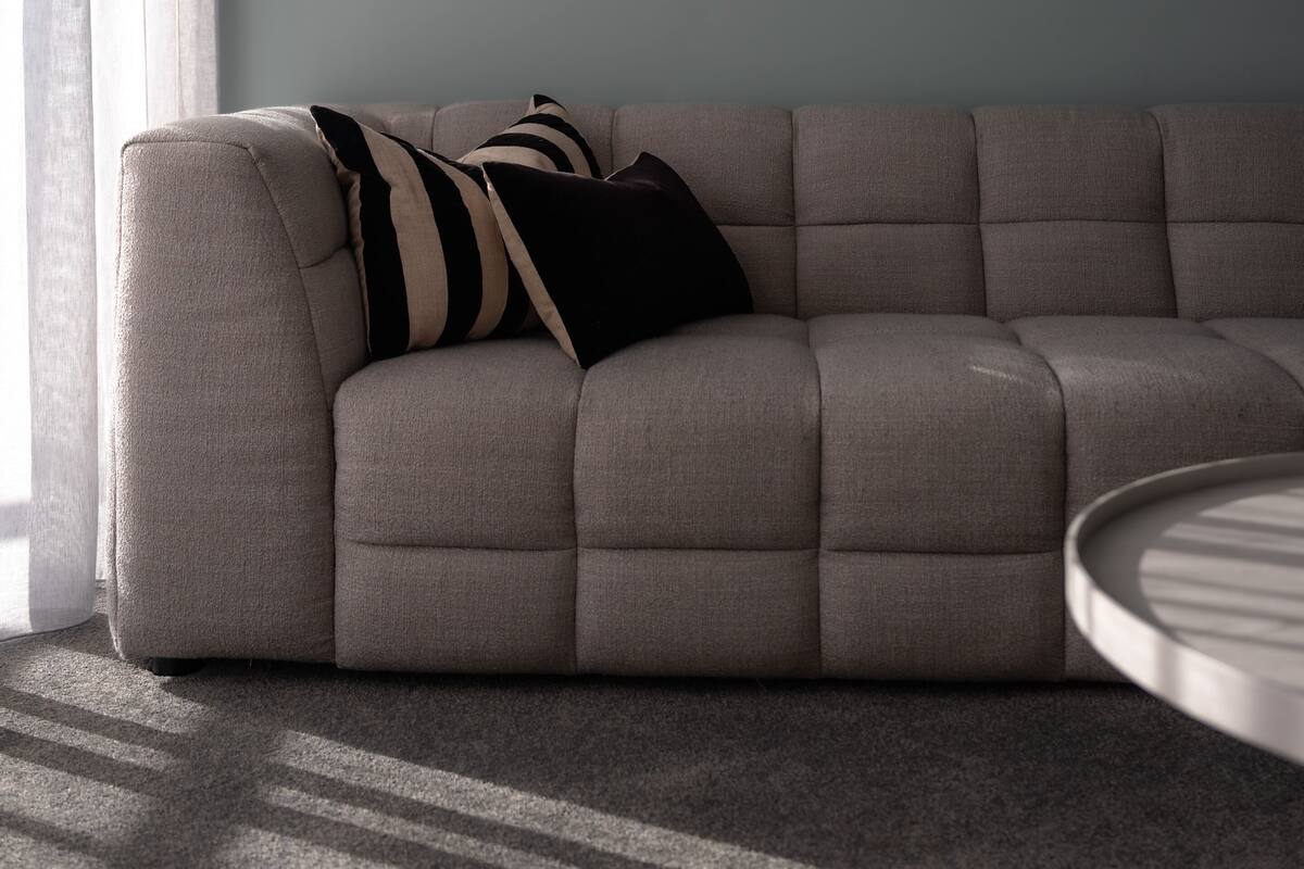 A modern living room with a grey sofa, a framed abstract artwork, and a round coffee table.