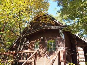 A rustic wooden cabin with a porch and a sign indicating it is a lodging facility. - Campagne Hakuba (Hakuba)