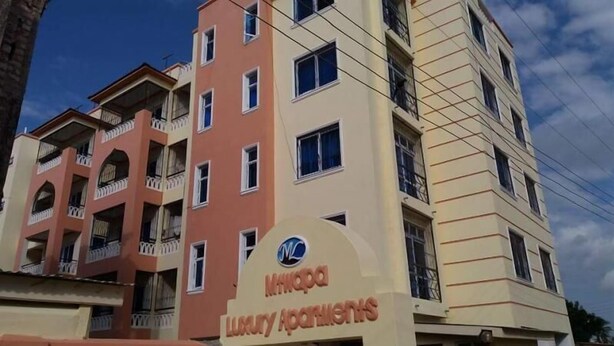 A multi-story building with balconies and a sign for "Minorca Luxury Apartments".