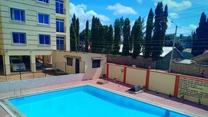 A swimming pool with a clear blue water, surrounded by a fence and a building with multiple windows.