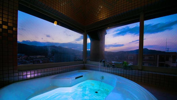 Un bain à remous avec vue sur le paysage urbain et les montagnes au crépuscule.