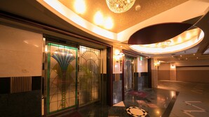 Un hall d’hôtel au design moderne, avec un plafond incurvé, un lustre et un sol à motifs.