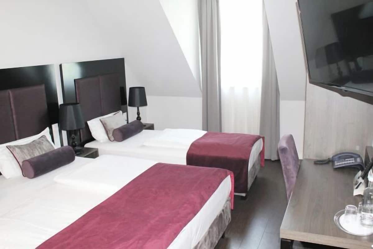 Hotellihuone, jossa on kaksi sänkyä, työpöytä ja televisio.