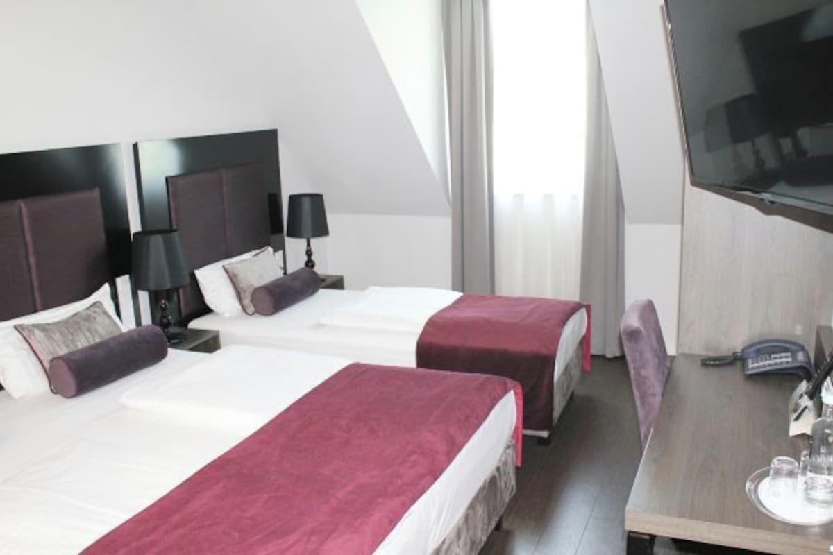 Une chambre d’hôtel avec deux lits, un bureau et une télévision.